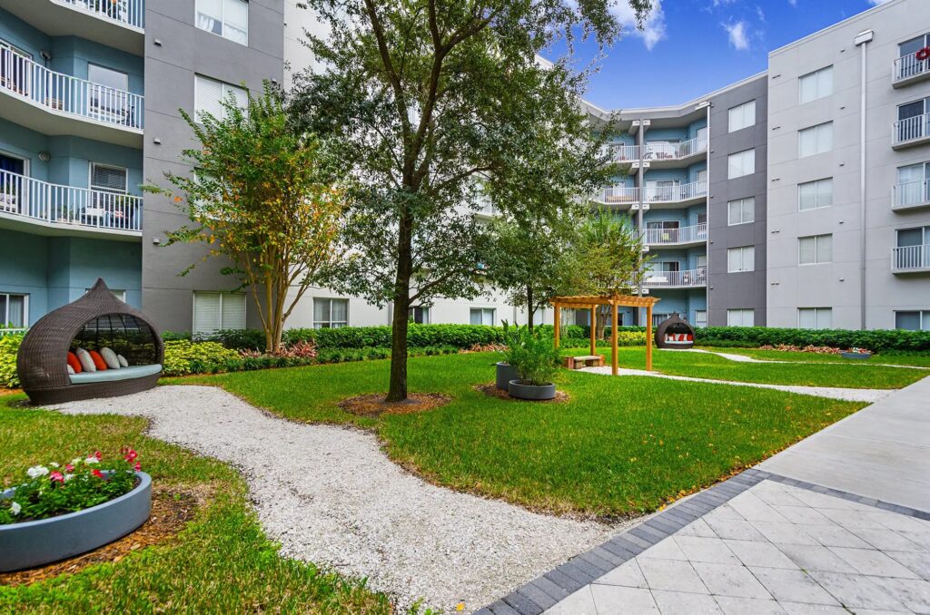 Courtyard with lots of grass and spaced out seating areas with residential building in the background