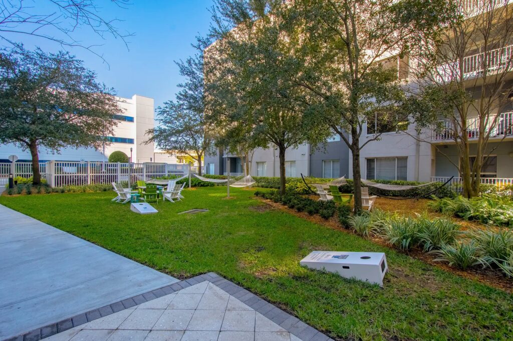 Courtyard with hammocks, corn hole board, fire pit, and chairs.