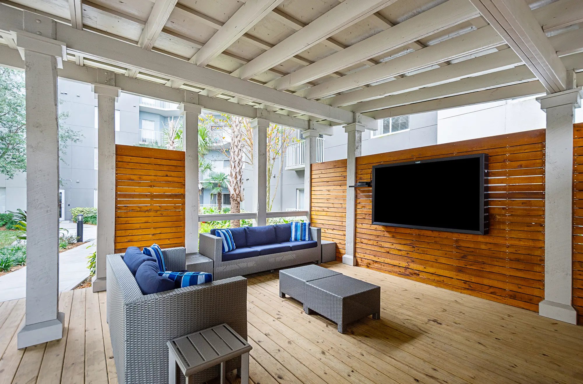 Outdoor covered seating area with couches and tv mounted on the wall