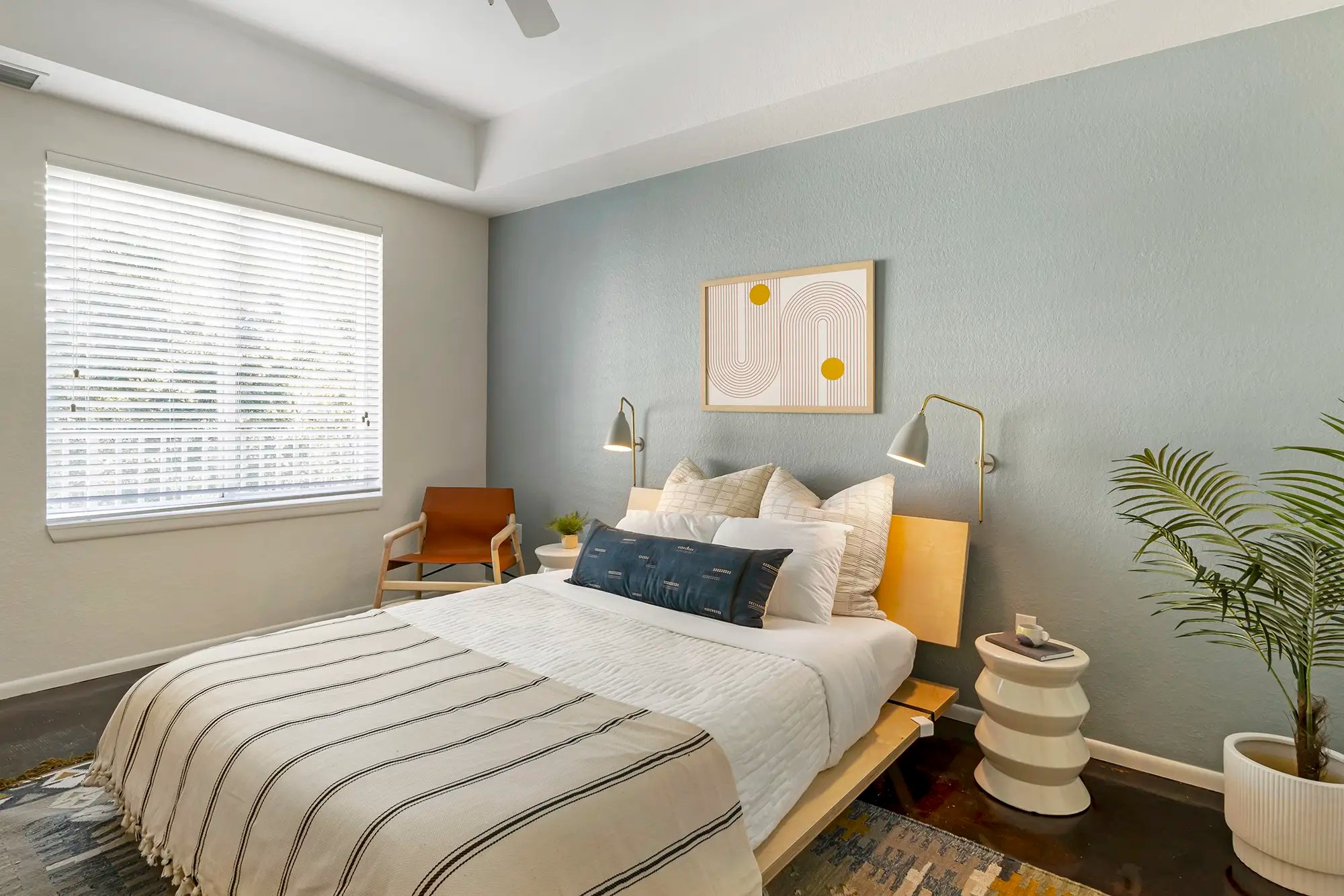 Bedroom with cement floors, large window, accent wall, and ceiling fan