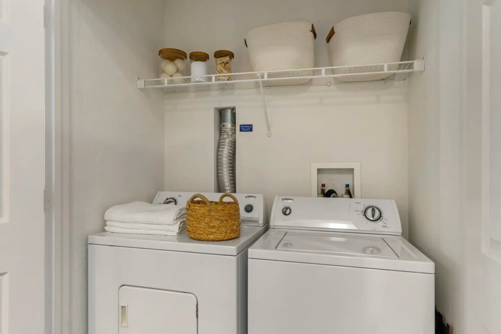 Open laundry room with washer and drier and built in shelf above.