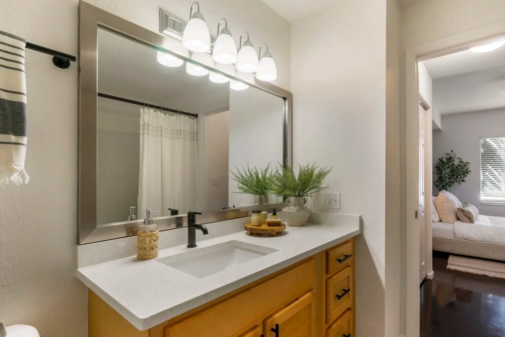 Bathroom with upgraded fixtures and large mirror with view of bedroom