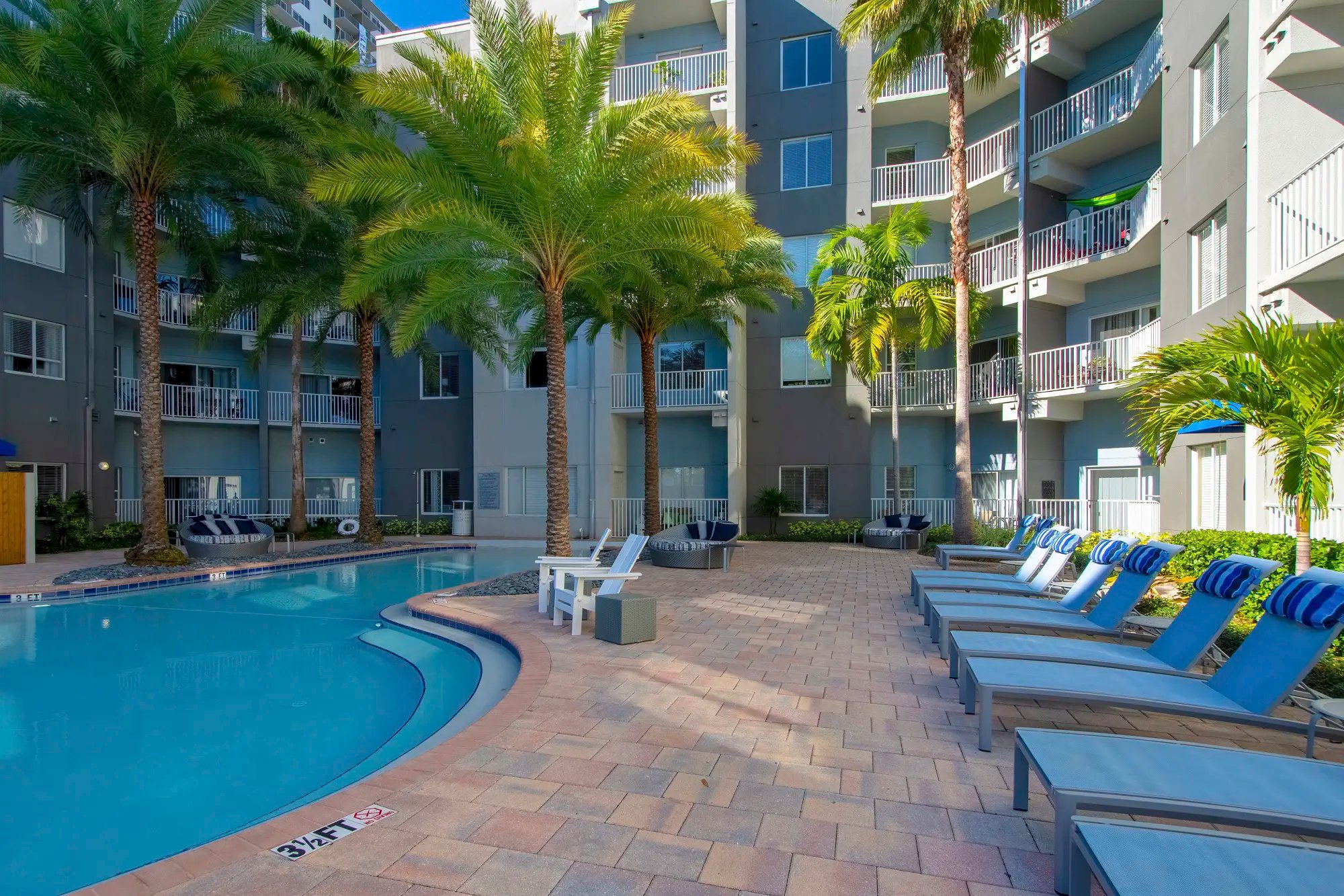 Pool with lounge chairs to the left and round chairs.